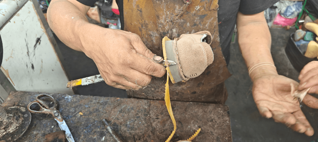 peruvain footwear market vendor cutting excess rubber from outsole on shoe