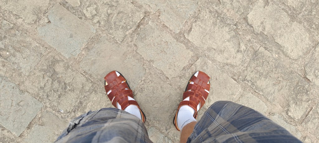 brown leather fisherman sandals with a large brick background as backdrop 