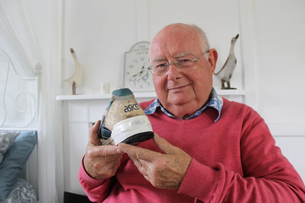 John Mott holding up the first prototype of the light up ASICS shoe which uses piezo-electric film strip for the flashing heel element