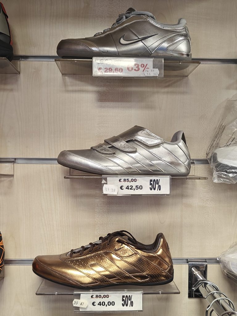 old 2000s nike women's shoe models on the shelf unit of an old sports shop in sicily