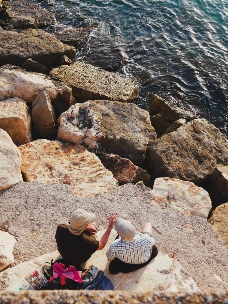 two old gentlemen chatting away on the jetty in peniscola spain captured from above